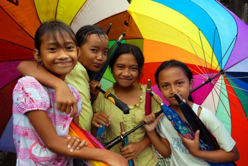 Indonesian girls offer to rent umbrellas to tourists in Bali.